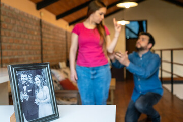 Pareja discutiendo y teniendo una pelea de pareja detrás de una foto de ellos felizmente casados....
