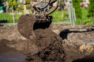 Muddy and dirty excavator digging ground and soil for coming construction project of building new houses