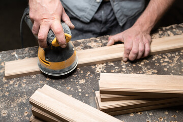 A carpenter grinds an oak part with a grinding machine