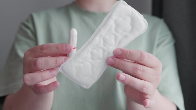 woman holding hygiene pad and tampon making decision of hygienic products choosing menstrual cup. choose alternative eco friendly variant of protection during menstruation.