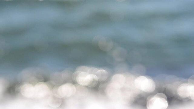 Sea view on a sunny summer day. Seascape. Sea landscape with blue sea water surface, small ripples and white bokeh spots with highlights of reflecting of the sun. Blurred abstract natural background
