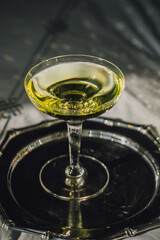 clear green drink in champagne coupe on silver tray