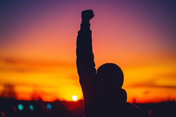 A powerful silhouette of a person in dynamic pose during a vibrant sunset, symbolizing strength and hope against the twilight sky