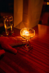 Man with empty cocktail glass at red lit bar, restaurant after meal