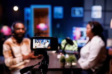 Detailed view of professional camera used to film live broadcast between show presenter and man in...