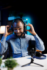 African american entertainer presenting headphones from brand sponsoring video, urging viewers to...