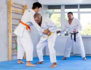 Focused senior man, karate sensei, engaging kumite with young guy, working out fighting techniques...