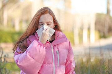 Woman with a cold blowing her nose with a handkerchief