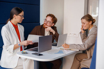 In a modern office setting, a diverse group of professionals is enthusiastically discussing various...