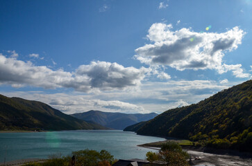 Naklejka premium View from Ananuri Fortress Complex to tranquil vibrant turquoise water surface of Zhinvali Water Reservoir nestled between rolling mountains with the lush greenery of the surrounding terrain. Georgia