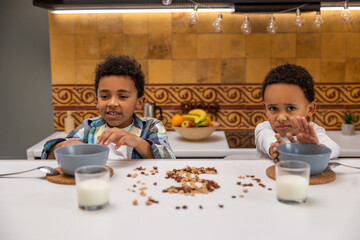 Siblings sitting at the table and rejecting food looking unhappy