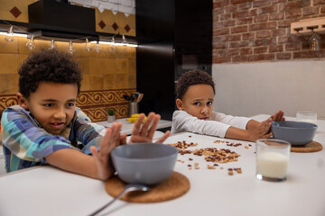 Siblings sitting at the table and rejecting food looking unhappy