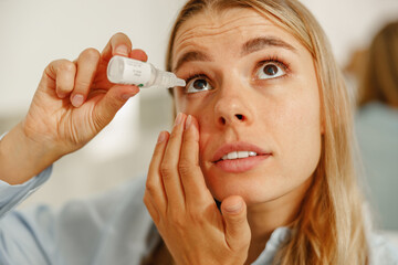 A person applies eye drops, highlighting the importance of eye care and hydration for vision and health