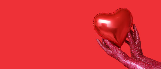 Female hands covered with glitters and heart-shaped balloon on red background with space for text. Valentines Day celebration