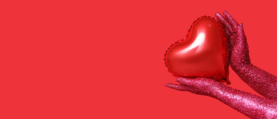 Female hands covered with glitters and heart-shaped balloon on red background with space for text. Valentines Day celebration