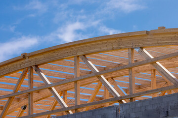 Construction detail of curved roof laminated timber beams or joists against a blue sky