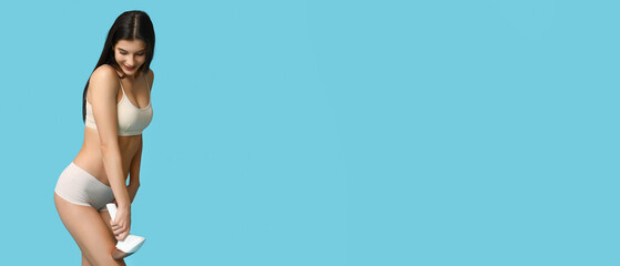 Beautiful young woman using modern photoepilator on light blue background with space for text