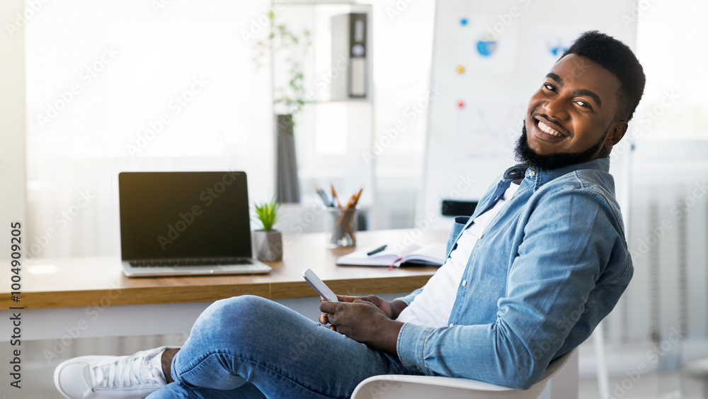 Poster portrait of cheerful african american employee using smartphone at workplace, browsing internet or m