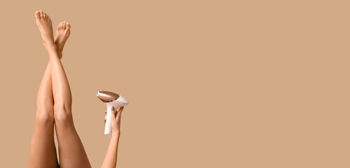 Young woman holding modern photoepilator on beige background with space for text