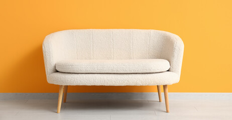Cozy white sofa near orange wall in room