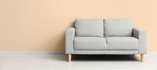 Cozy grey sofa near beige wall in room. Banner for design