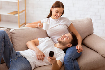 Weekend Concept. Smiling Couple Watching TV Relaxing Together Sitting On Sofa At Home. Selective Focus