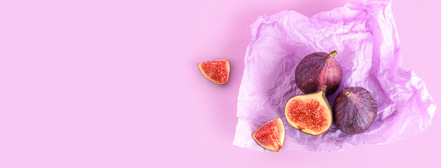 Fresh juicy cut figs with paper on lilac background