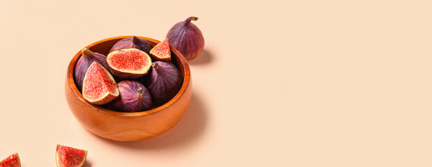 Bowl with fresh juicy cut figs on pale pink background