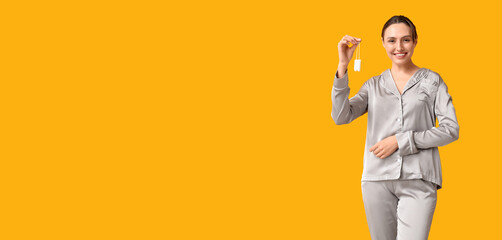 Beautiful young woman with tampons on yellow background