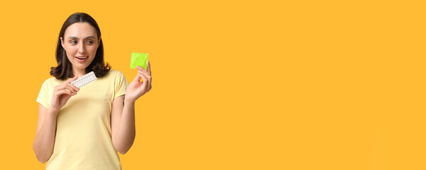 Beautiful young woman with condom and birth control pills on yellow background. Safe sex concept