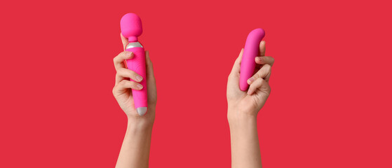 Female hands with vibrators on red background, closeup