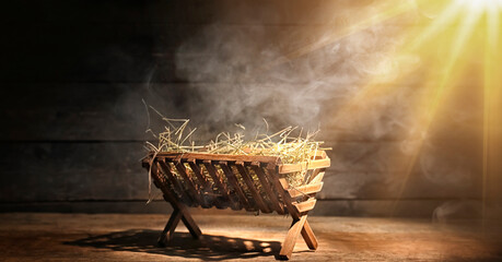 Manger with hay and smoke on dark wooden background