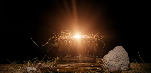 Manger with baby, hay, old book and stones on wooden table against dark background