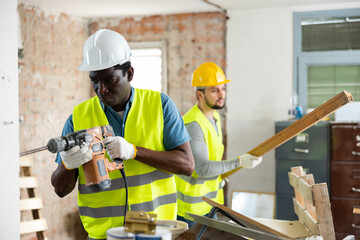 Two qualified builders carry out major repairs in the house, working on the construction site...