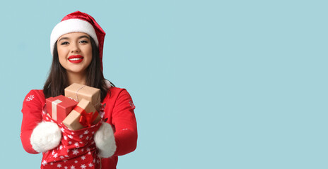 Pretty young woman with bag of Christmas gifts on blue background