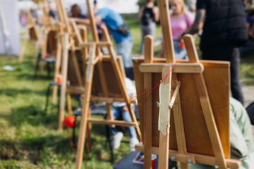 Kids drawing at plein air, group class of talented children with painting easel and wooden canvas during lesson of watercolor painting outdoors, drawing class for young teen artists in art school