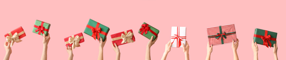 Female hands holding Christmas gift boxes on pink background