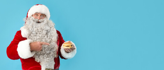 Santa Claus pointing at tasty burger on blue background