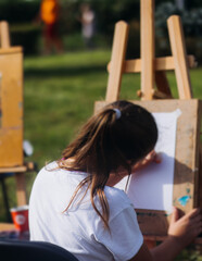 Kids drawing at plein air, group class of talented children with painting easel and wooden canvas during lesson of watercolor painting outdoors, drawing class for young teen artists in art school