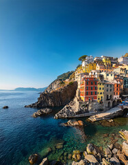 Naklejka premium Colorful cliffside village overlooking serene sea with boats