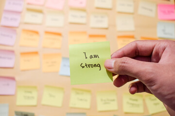 Hand hold sticky notes with words I am strong, Motivational for personal development, inspirational...