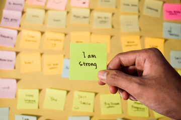 Hand hold sticky notes with words I am strong, Motivational personal development, inspirational...