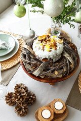 Festive table setting for Christmas dinner with cake, burning candles and pine cones