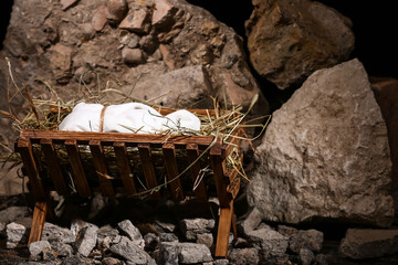 Manger with baby and hay on stones, closeup