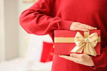 Woman holding gift box at home on Christmas eve, closeup