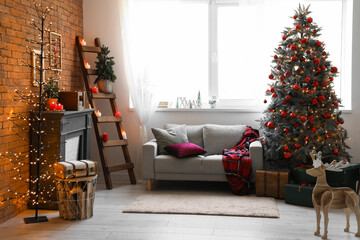 Interior of festive living room with Christmas tree, fireplace and grey sofa near window