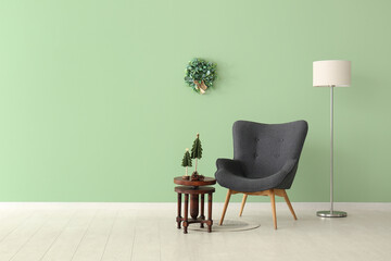 Grey armchair and Christmas decor on wooden table near green wall
