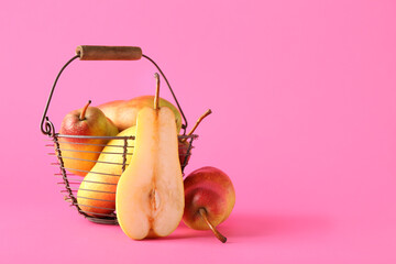 Basket with ripe pears on pink background