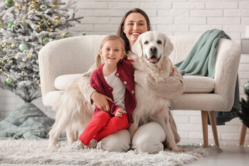 Happy young mother and her little daughter with cute Labrador dog at home on Christmas eve