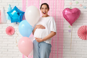 Beautiful happy pregnant woman with balloons on white brick background. Gender reveal party concept
